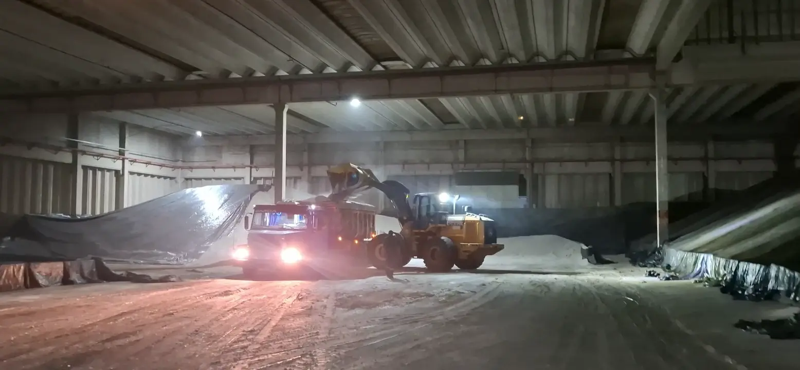 Vídeo da pá carregadeira John Deere 724 carregando um caminhão em operação noturna no interior de um armazém