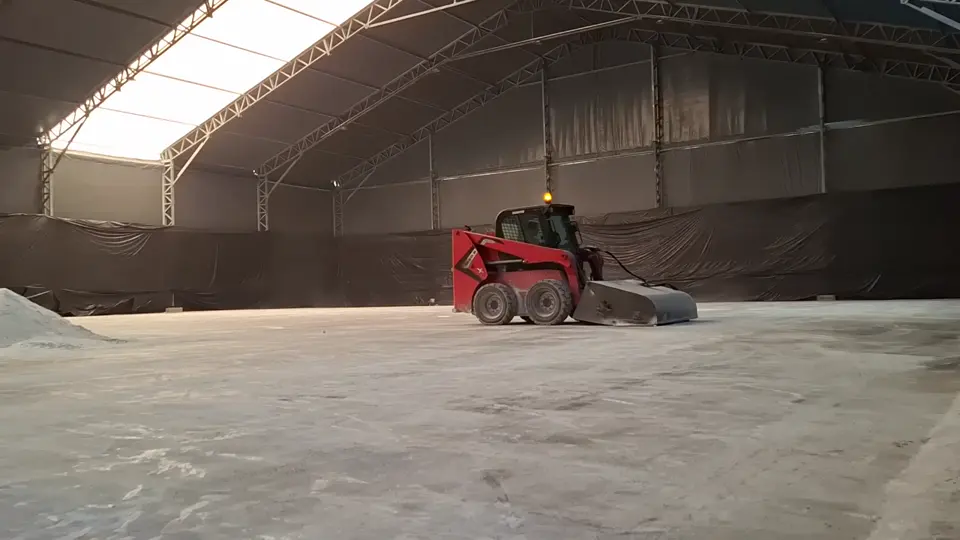 Vídeo da minicarregadeira Manitou 1650R com varredeira limpando piso de armazém lonado